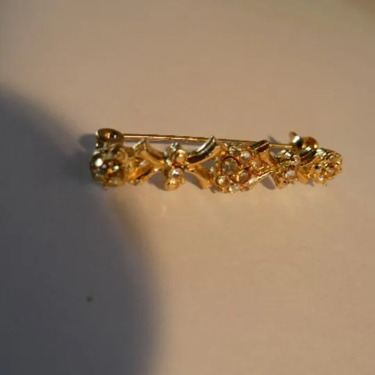 Jolie petite broche en métal doré parsemer de strass 